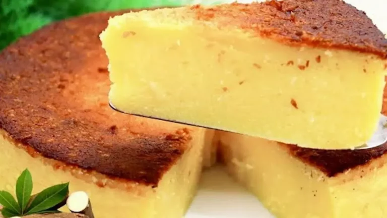 Bolo de aipim cremoso recém-assado com topo dourado sobre mesa rústica.